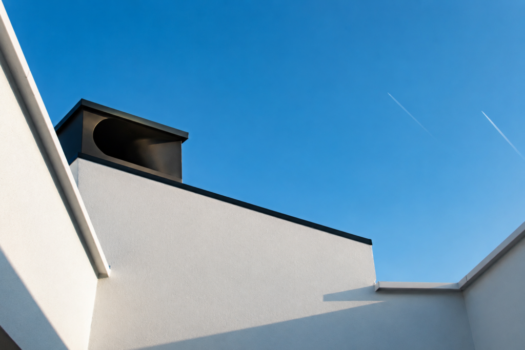 Détail architectural d’une villa contemporaine à Kain conçue par Loyd Architects, mettant en valeur une cheminée design, des lignes épurées et une architecture durable baignée de lumière naturelle.